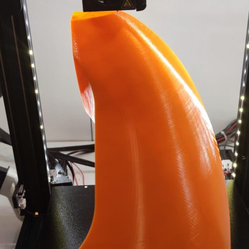 Pieza naranja siendo impresa en una impresora 3D